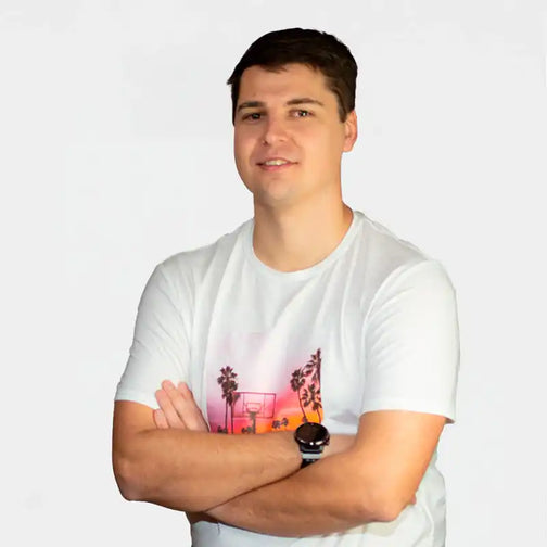 A person wearing a white t-shirt with a sunset palm tree design and a watch.