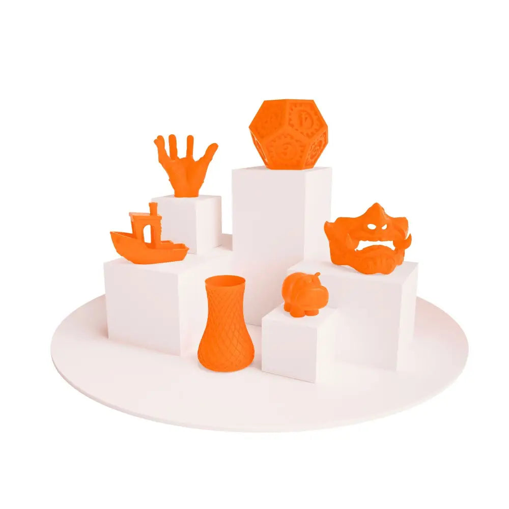Display of vibrant orange 3D printed objects using PLA Neon Filament for creative projects