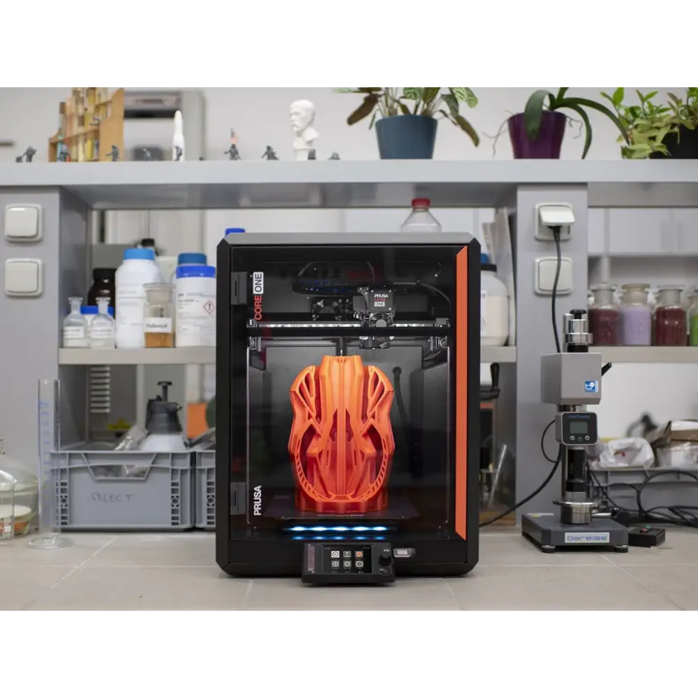3D printer with orange helmet-shaped object inside.