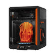 Black and orange 3D printer with orange object inside.