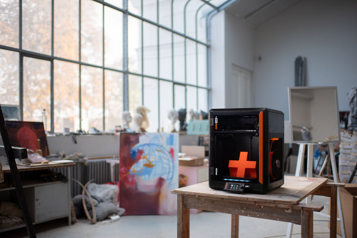 Geschlossener CoreXY-3D-Drucker Prusa CORE One+ auf einem Tisch in einem hellen Designstudio