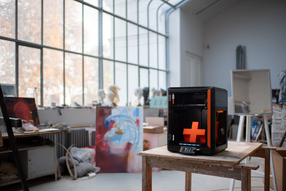 Geschlossener CoreXY-3D-Drucker Prusa CORE One+ auf einem Tisch in einem hellen Designstudio