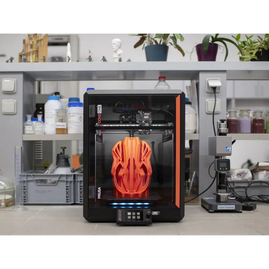 3D printer with orange helmet-shaped object inside.