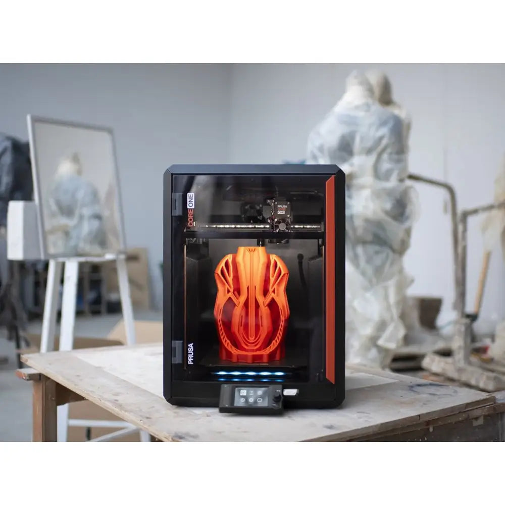 Black and orange 3D printer with transparent enclosure.